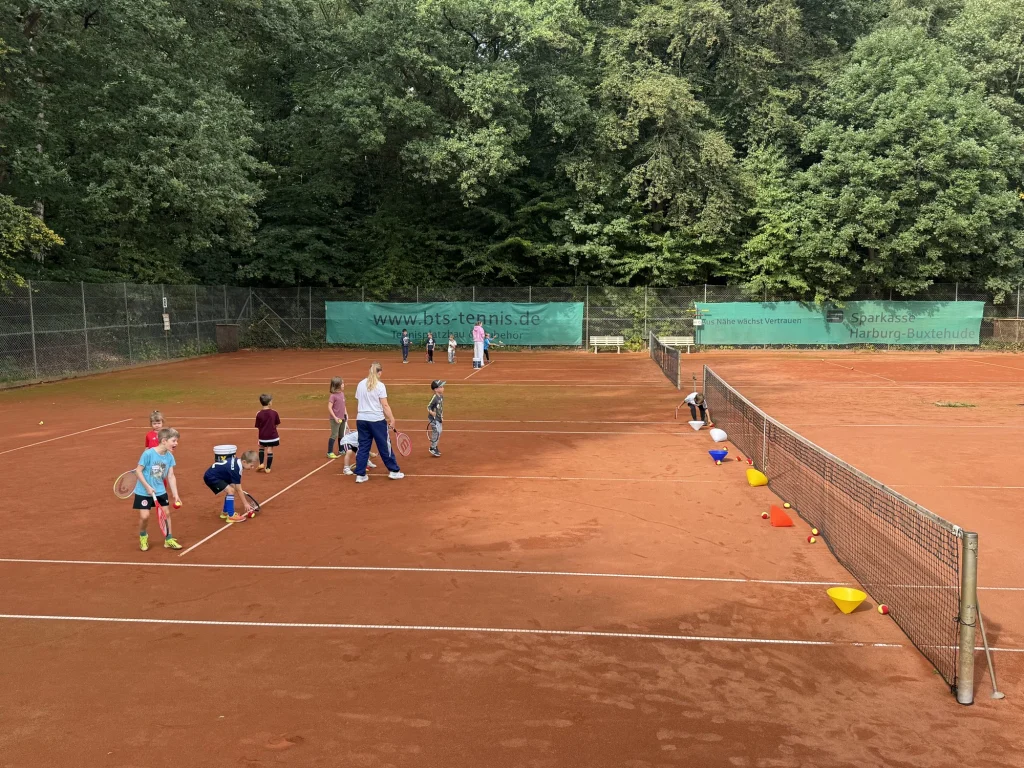 Kleine Gruppen üben mit Bällen und Hütchen auf den Sandplätzen