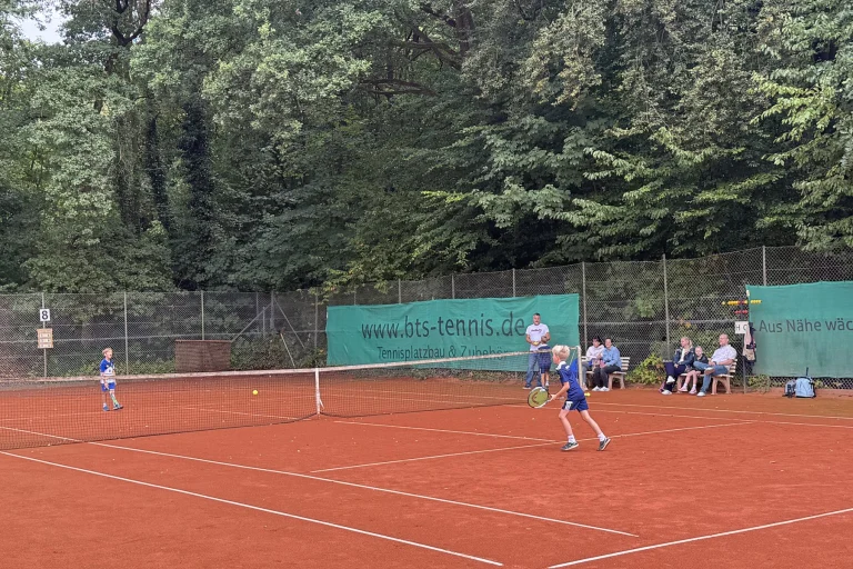 Jugendliche spielen beim Freundschaftsturnier auf dem Sandplatz, Zuschauer am Rand