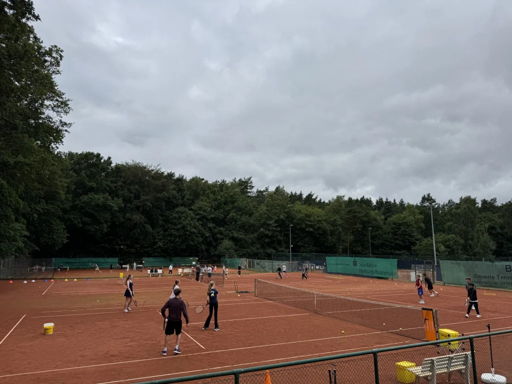 Jugendliche beim Grundschlagtraining auf mehreren Sandplätzen